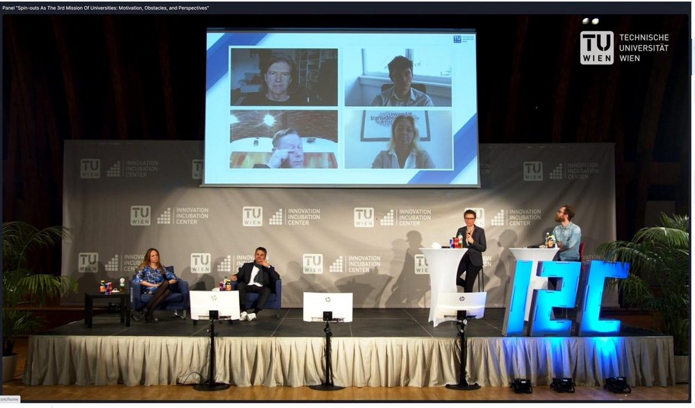 Paneltalk: 4 Personen sitzend auf der Bühne und 4 Personen auf der Leinwand via Videochat zugeschaltet. 