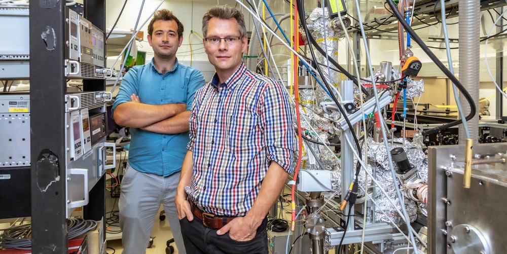 Zwei TU Graz Forscher in einem Physiklabor, zwischen Kabeln und Geräten