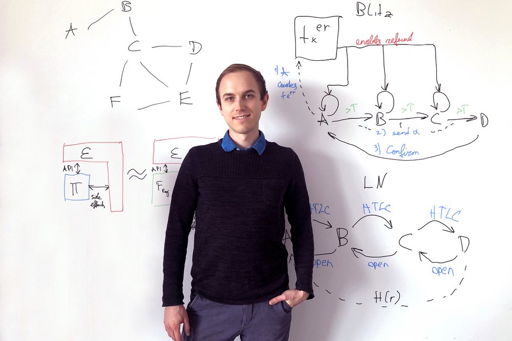 Lukas Aumayr in front of a white wall with formulas on it.