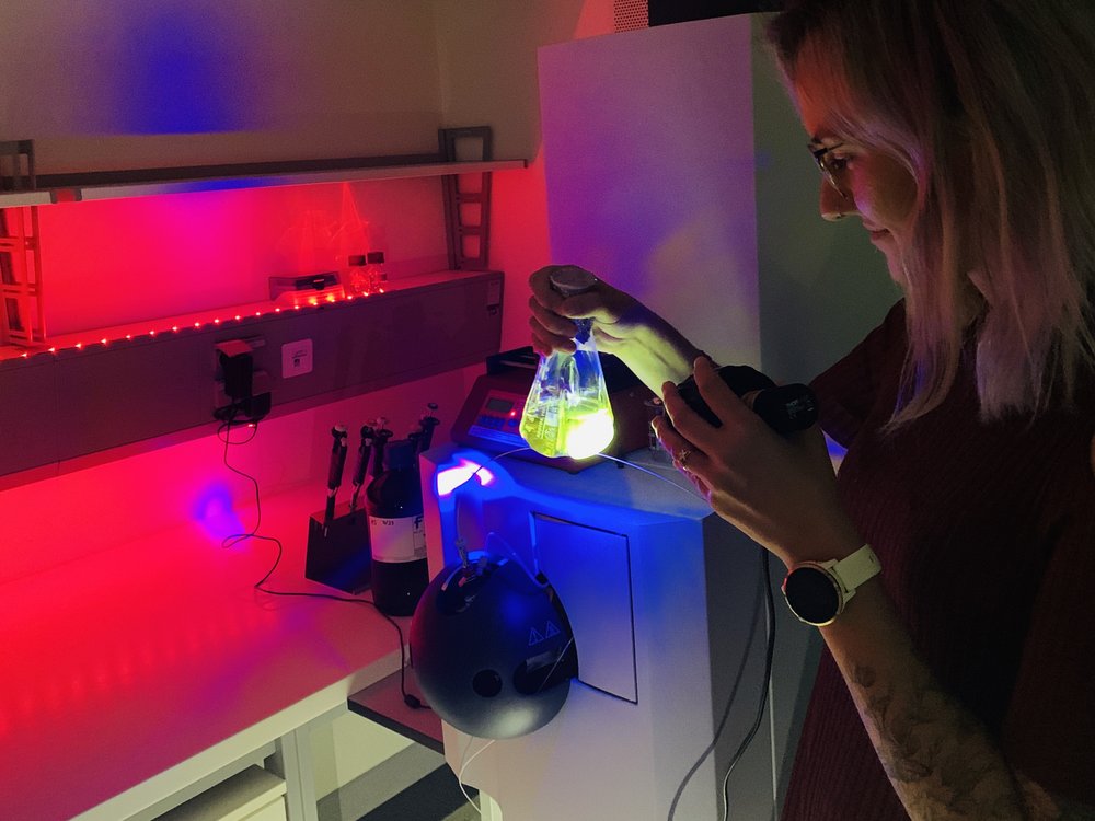 Eine Frau in einem Labor hält einen leuchtenden Glasbehälter