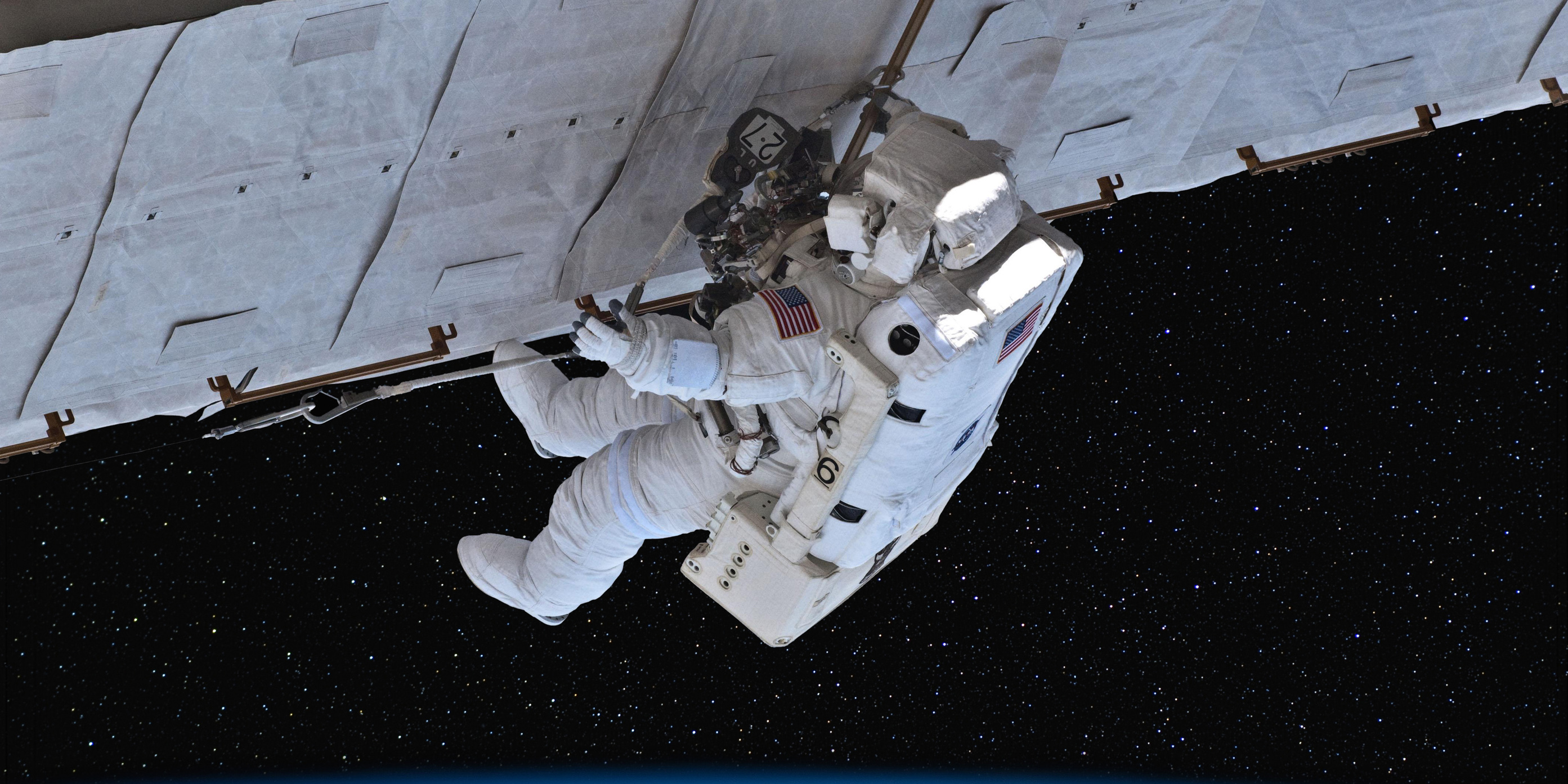 Astronaut wearing a white space suit working in space.